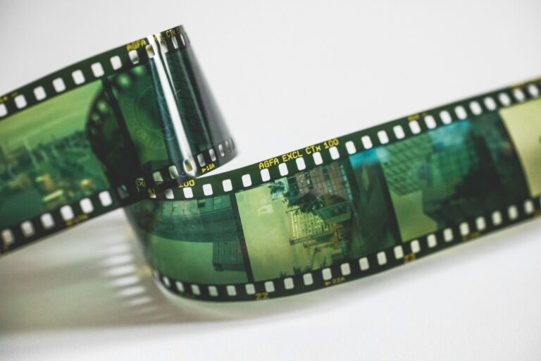 Bande de film argentique déroulée sur fond blanc, illustrant la numérisation de pellicules et de bobines